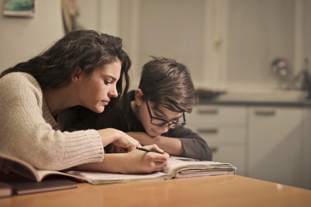 An image of a mother helping her son focus on homework